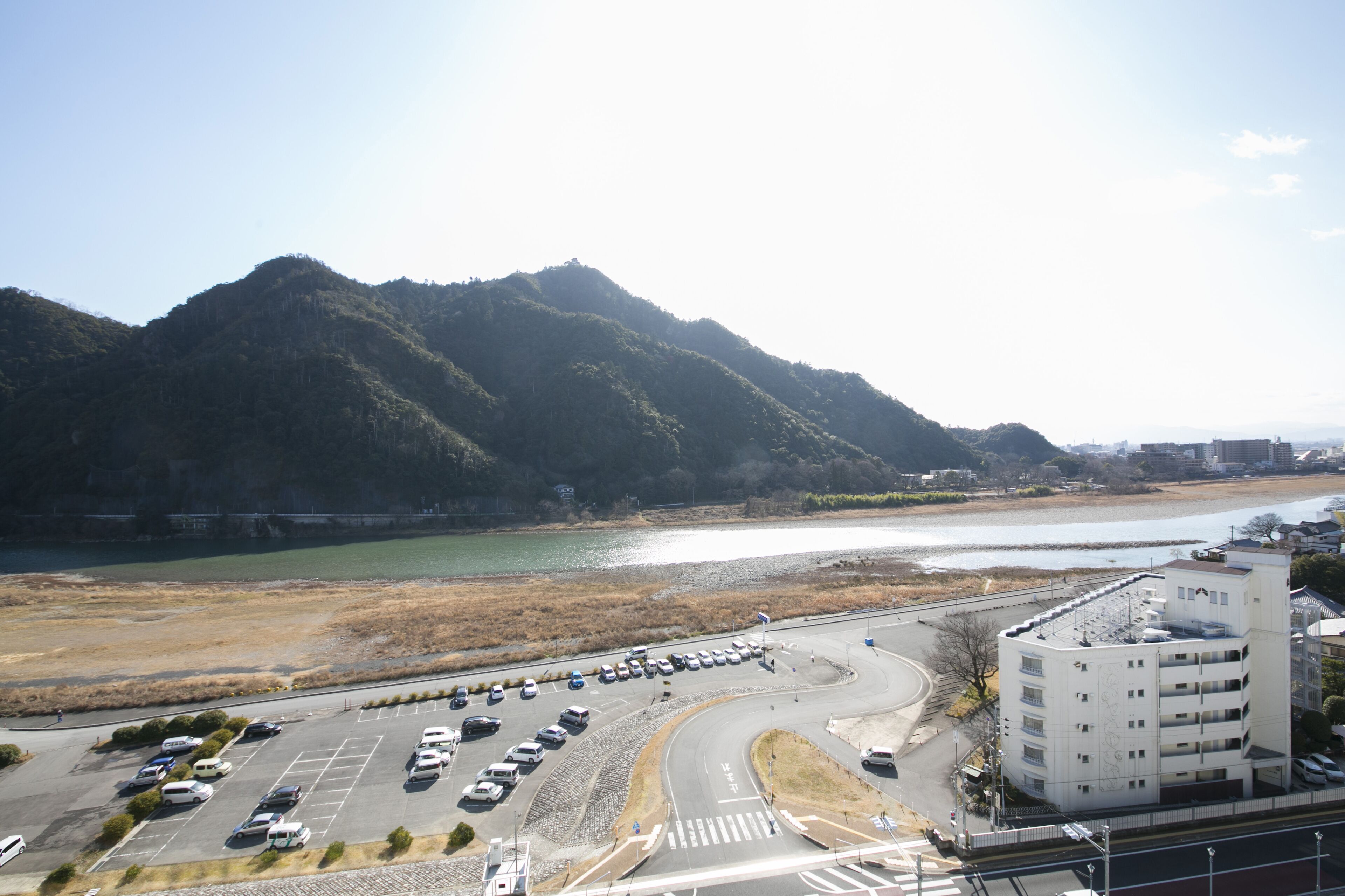 A parking lot with cars, a roundabout, and a building with multiple floors.