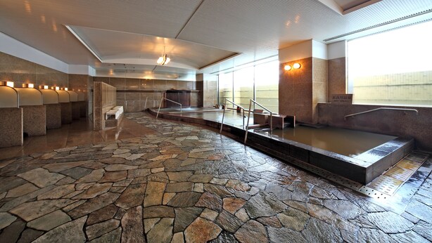 A stone-floored spa area with a hot tub, seating, and a view of the outdoors. - Gifu Grand Hotel (Gifu)
