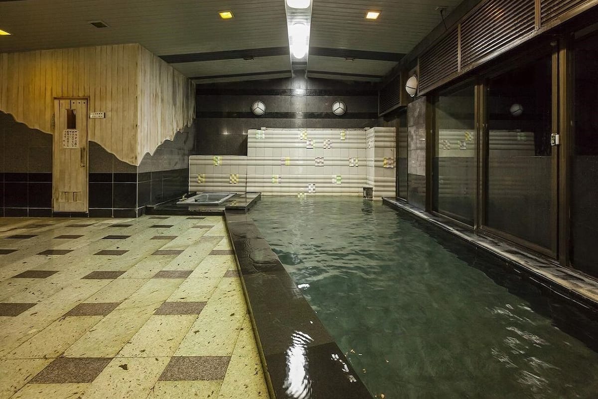 Une piscine intérieure avec un sol carrelé et un mur en bois.