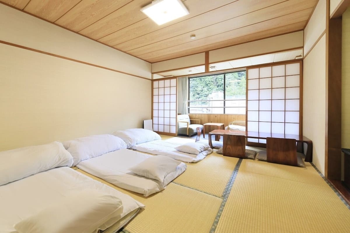 Une pièce de style japonais traditionnel, avec un sol recouvert de tatamis, un plafond bas en bois et des portes coulissantes en papier de riz (shoji).