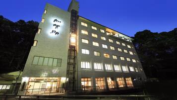 A multi-story hotel with a prominent sign on the facade, multiple windows, and a balcony area.