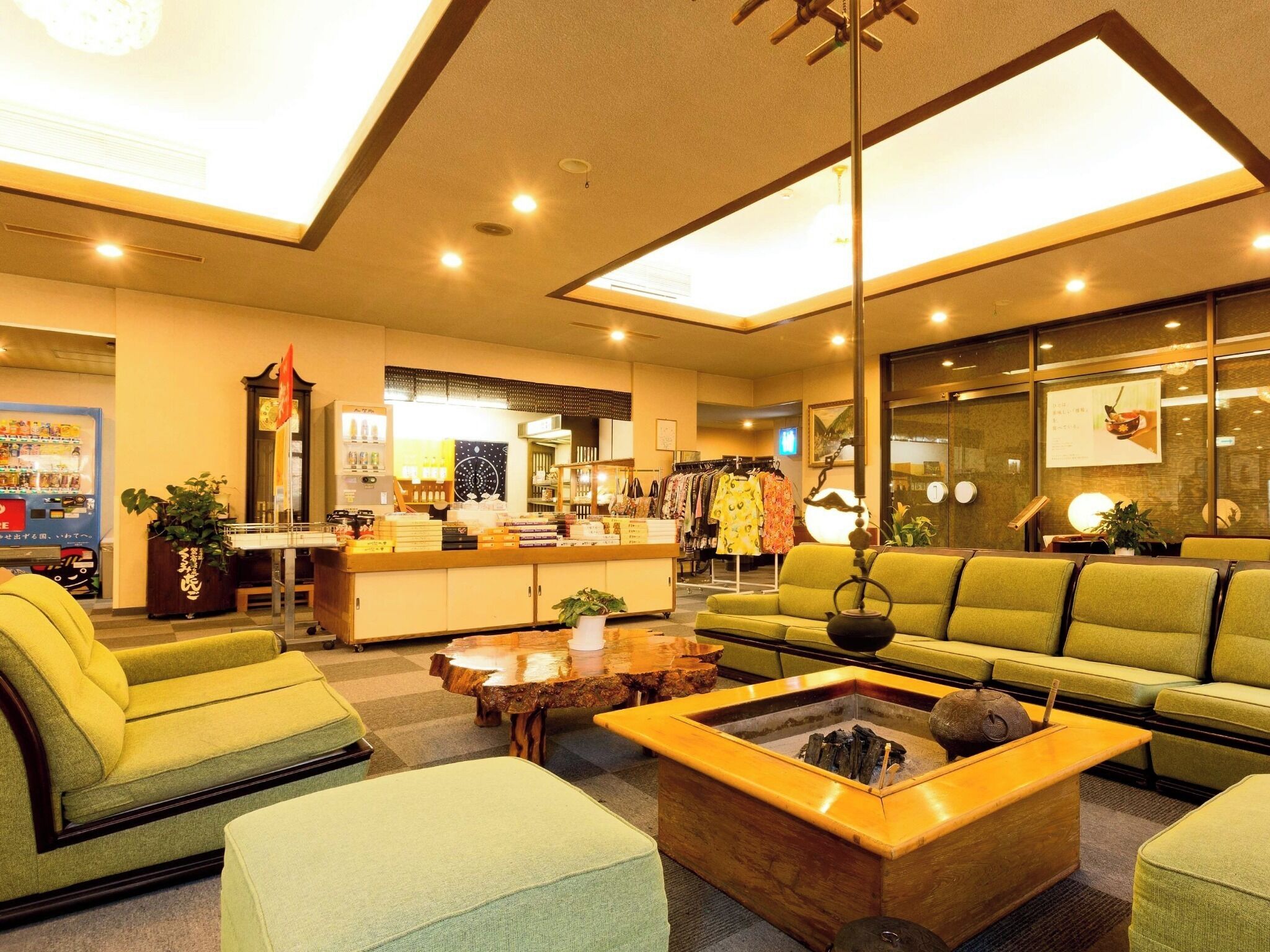 A hotel lobby with a sofa, chairs, a coffee table, a reception desk, and a clothing store.