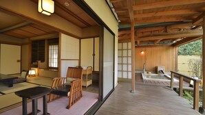 Une pièce de style japonais traditionnel, avec un sol recouvert de tatamis, une table basse avec des coussins et des portes coulissantes.