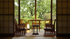 Une pièce de style japonais traditionnel, avec un sol recouvert de tatamis, une table basse et des chaises en bois.