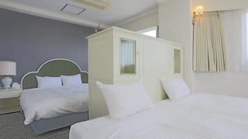 Una habitación de hotel con dos camas, una mesita de noche con lámpara y un armario.