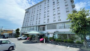 Ein mehrstöckiges Hotel mit modernem Design, mit einem überdachten Eingangsbereich und einer Glaskuppel sowie einem Schild, das es als Hotel kennzeichnet.