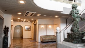 Eine Lobby mit Schachbrettmuster-Boden, einer Statue, einer Treppe und einem gerahmten Bild an der Wand.