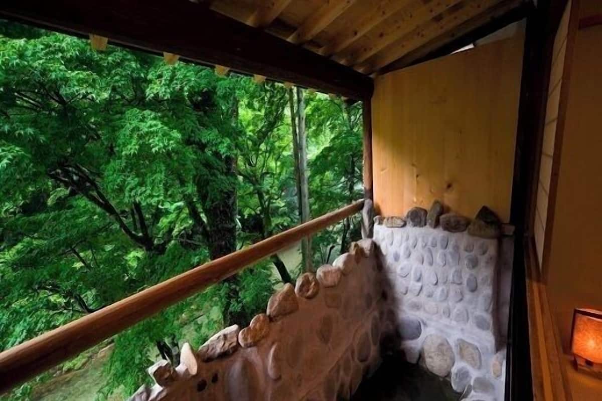 Ein Badebereich mit Steinsäulen und Holzgeländer, umgeben von üppigem Grün.