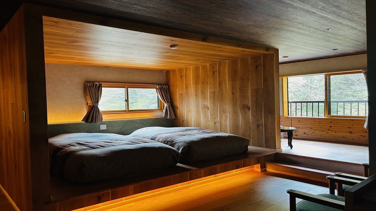Una camera in una baita di legno con un letto, finestre e vista sull'esterno.