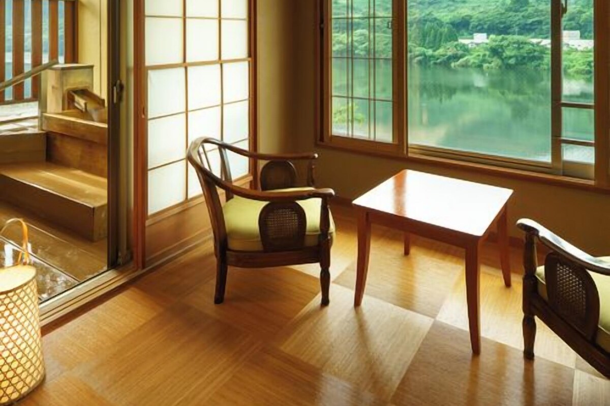 Une pièce avec vue sur un lac et des montagnes, dotée d’un plancher en bois, d’une table et d’une chaise.