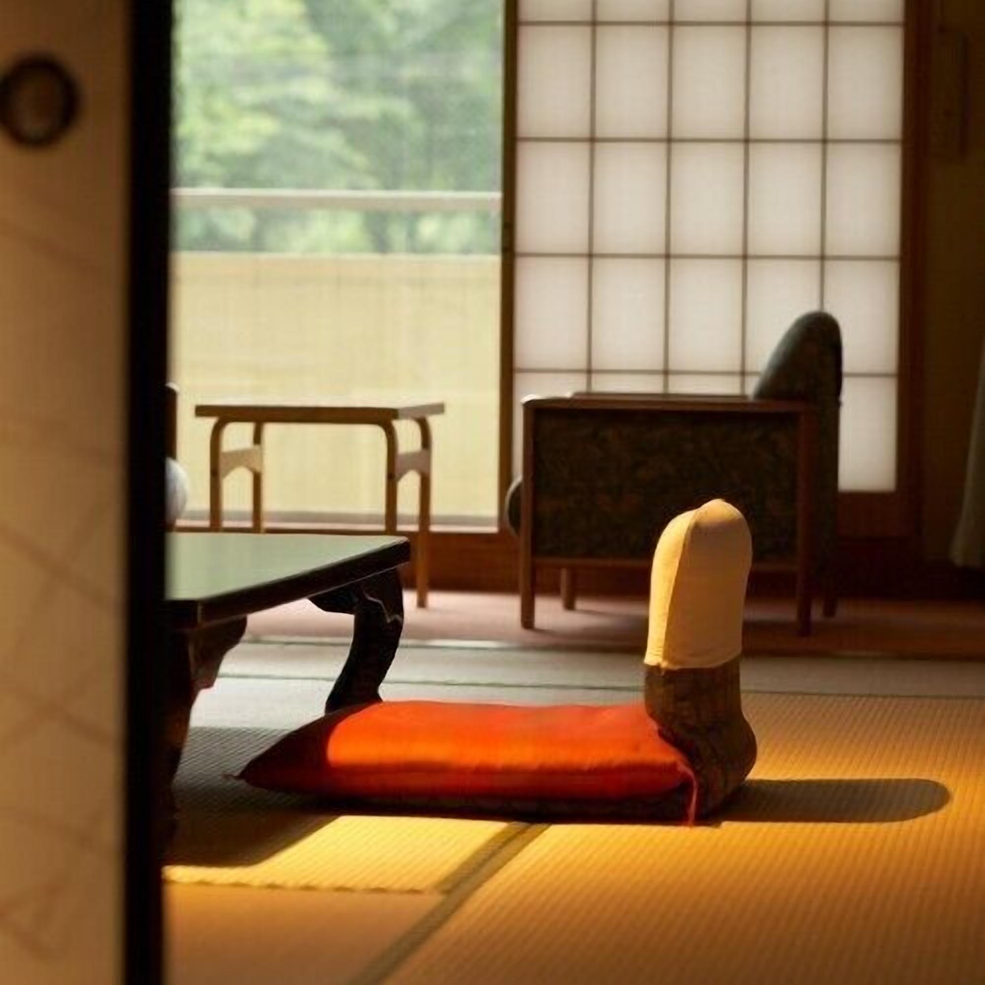 Una habitación con esteras de tatami, una mesa baja y una silla.