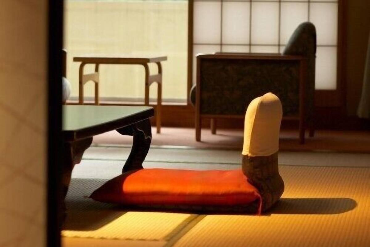 Una habitación con esteras de tatami, una mesa baja y una silla.