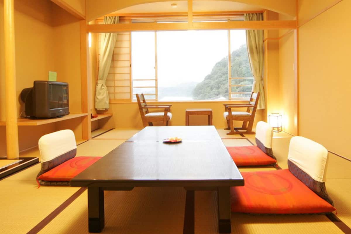 Una habitación con una mesa grande, sillas, televisión y vistas a la montaña.