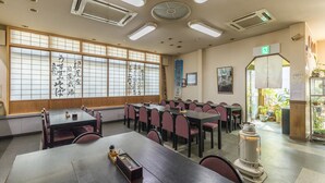Un salón de conferencias con un tradicional panel japonés shoji, varias mesas, sillas y un calentador.