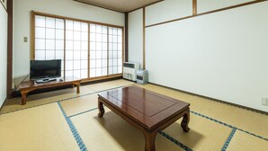 Una habitación japonesa tradicional con suelo de tatami, televisor, calentador y puertas correderas shoji.