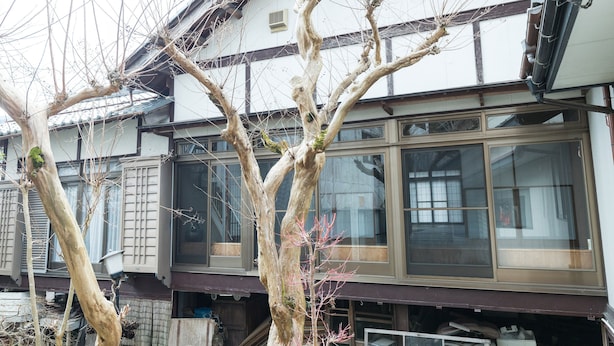 Una casa japonesa tradicional con fachada de madera, ventanas grandes y una escalera visible que conduce a la entrada.
