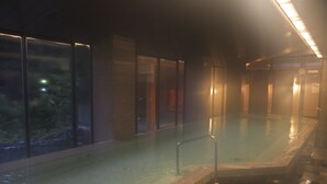 A large indoor swimming pool with clear glass walls, a tiled floor, and a railing around the pool. - Kashiwaya (Nikko)