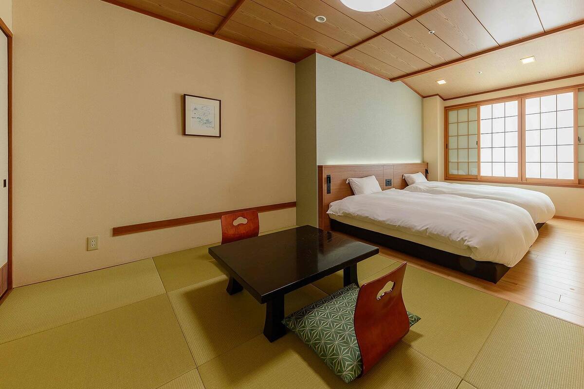 Une chambre d’hôtel avec un lit, une table et un futon.