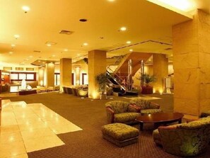 A spacious lobby with a reception desk, seating area, and a staircase.