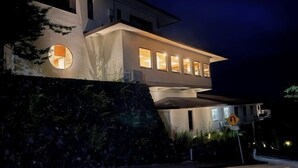 A modern house with a flat roof, large windows, and a driveway. - Izu One Club (Ito)