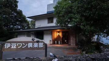 Un edificio con un cartel que dice '伊豆ワン便栄部'.