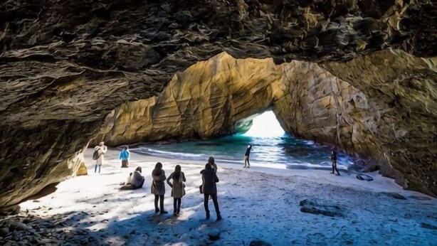 A natural rock arch formation with a beach in front. - Izu One Club (Ito)