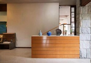 A wooden reception desk with a blue vase and a clock. - Izu One Club (Ito)