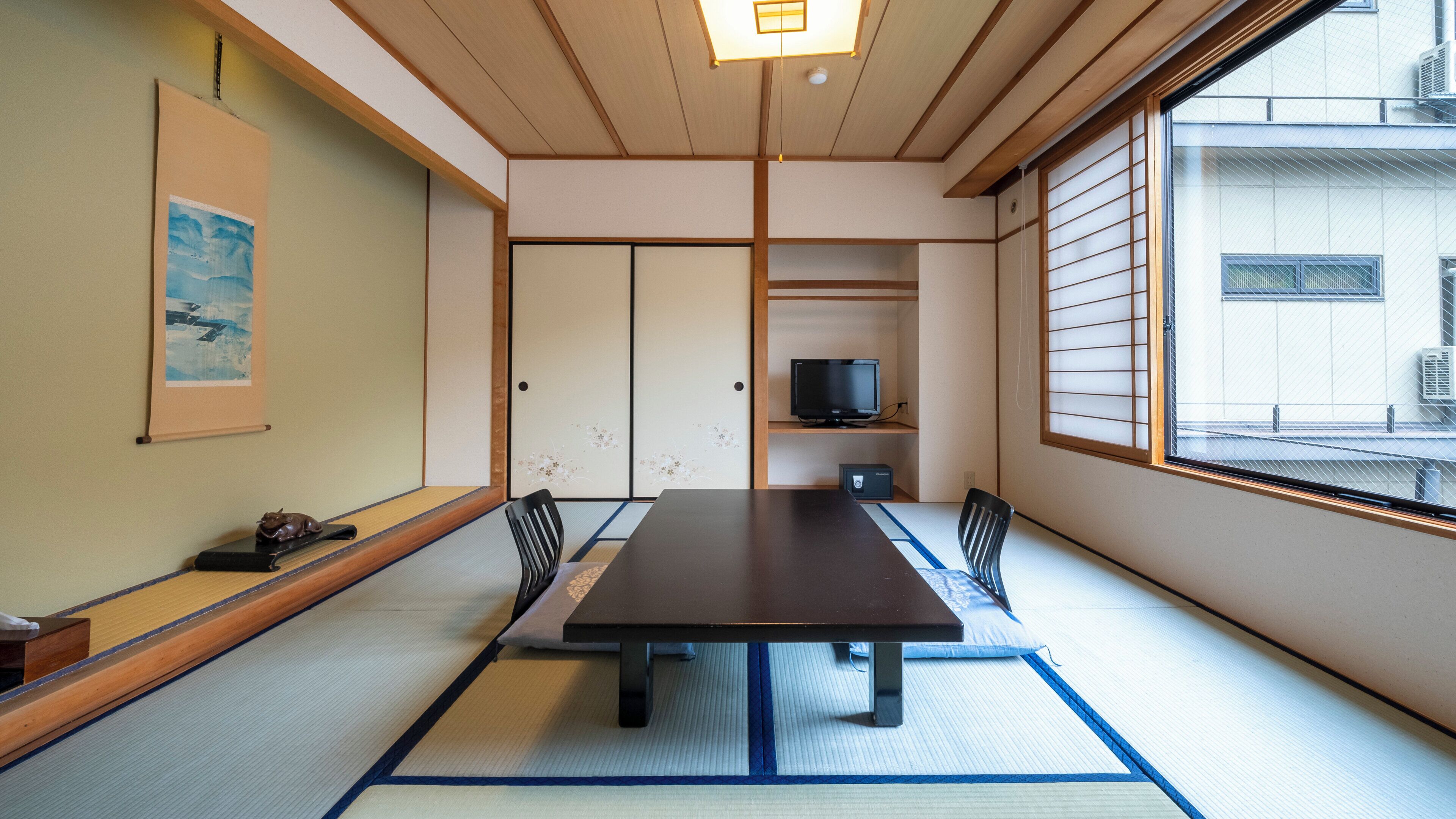 A traditional Japanese room with tatami flooring, a low table, and sliding doors.