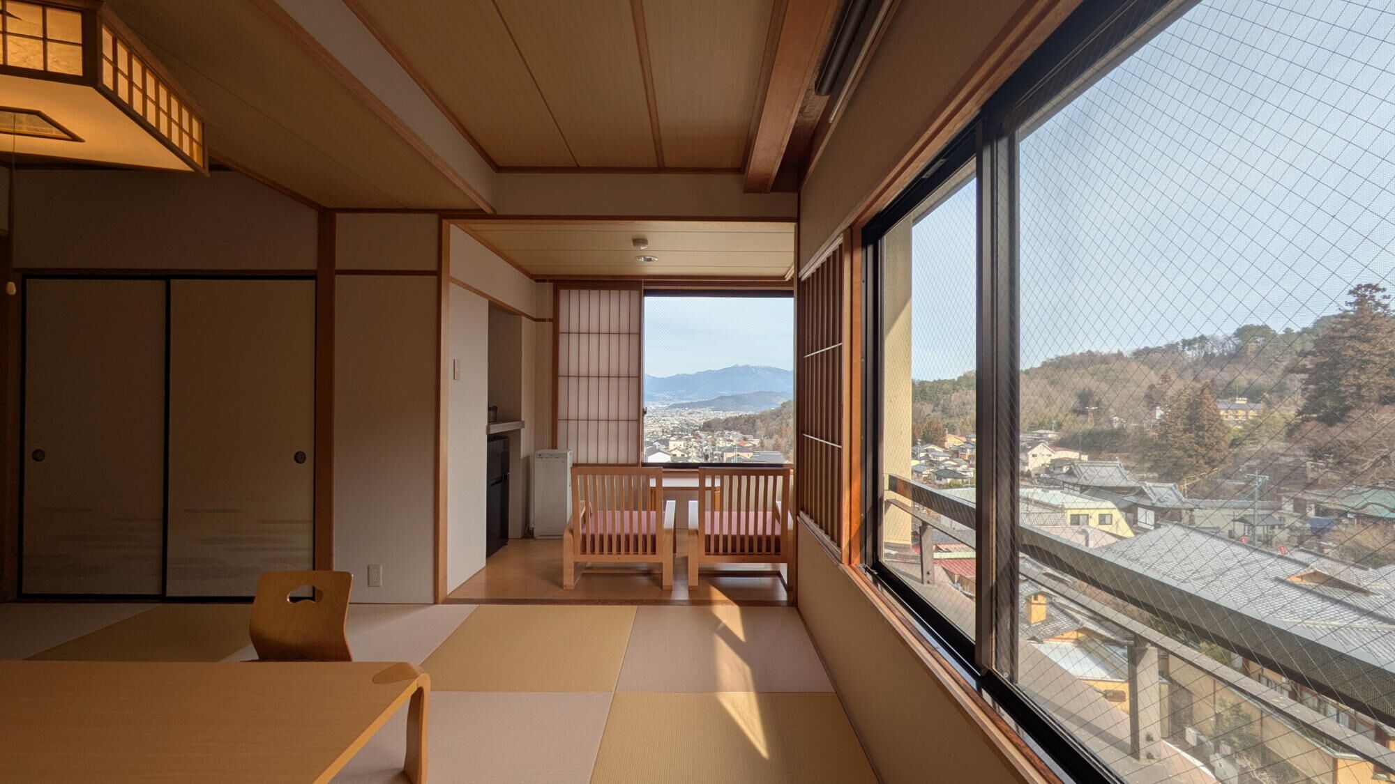 Una habitación japonesa tradicional con suelo de tatami, una mesita baja, un banco y una puerta corredera.