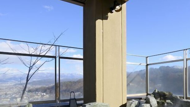 A hot spring with clear water, rocks, and a view of mountains. - Ryokan Nakamatsuya (Nagano)