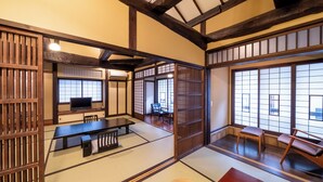 A traditional Japanese room with tatami flooring, a low table, a television, and sliding doors. - Ryokan Nakamatsuya (Nagano)