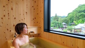 A wooden room with a window, a bathtub, and a view of traditional buildings. - Ryokan Nakamatsuya (Nagano)