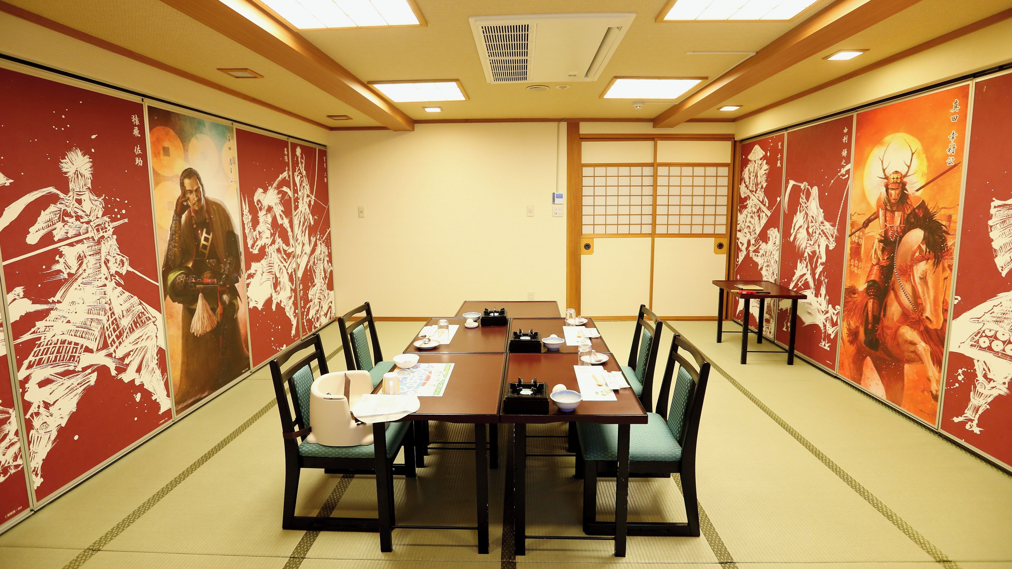 Une salle de conférence avec une longue table, des chaises et un décor japonais traditionnel.