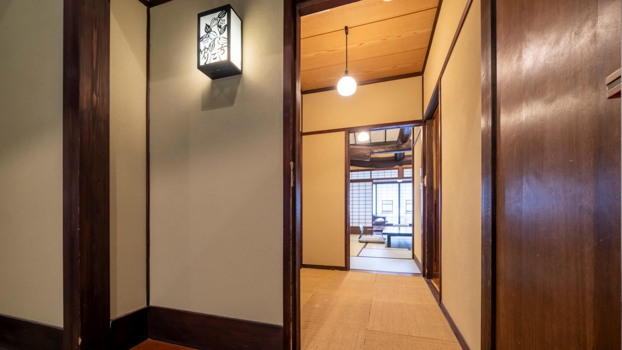 Un interior japonés tradicional con suelo de tatami, puertas correderas y una lámpara colgante.