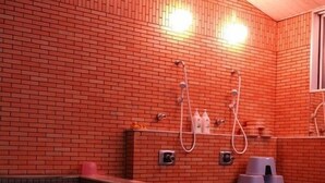 Una piscina con pared de ladrillo, duchas y una ventana.