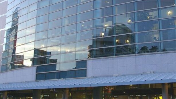 Un edificio moderno con fachada de vidrio, un cartel que dice 'TOKUSHIMA STATION' y una estructura de techo curva.