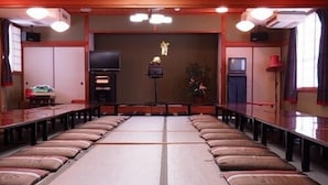 Una habitación con esteras de tatami, una mesa larga y cojines.