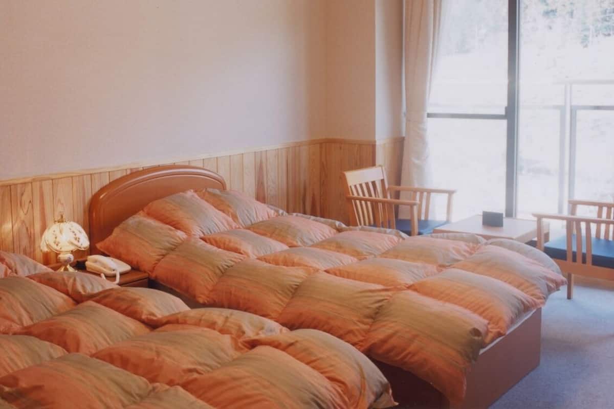 Une chambre d’hôtel avec un grand lit, une table de chevet, une lampe et une fenêtre avec des rideaux.