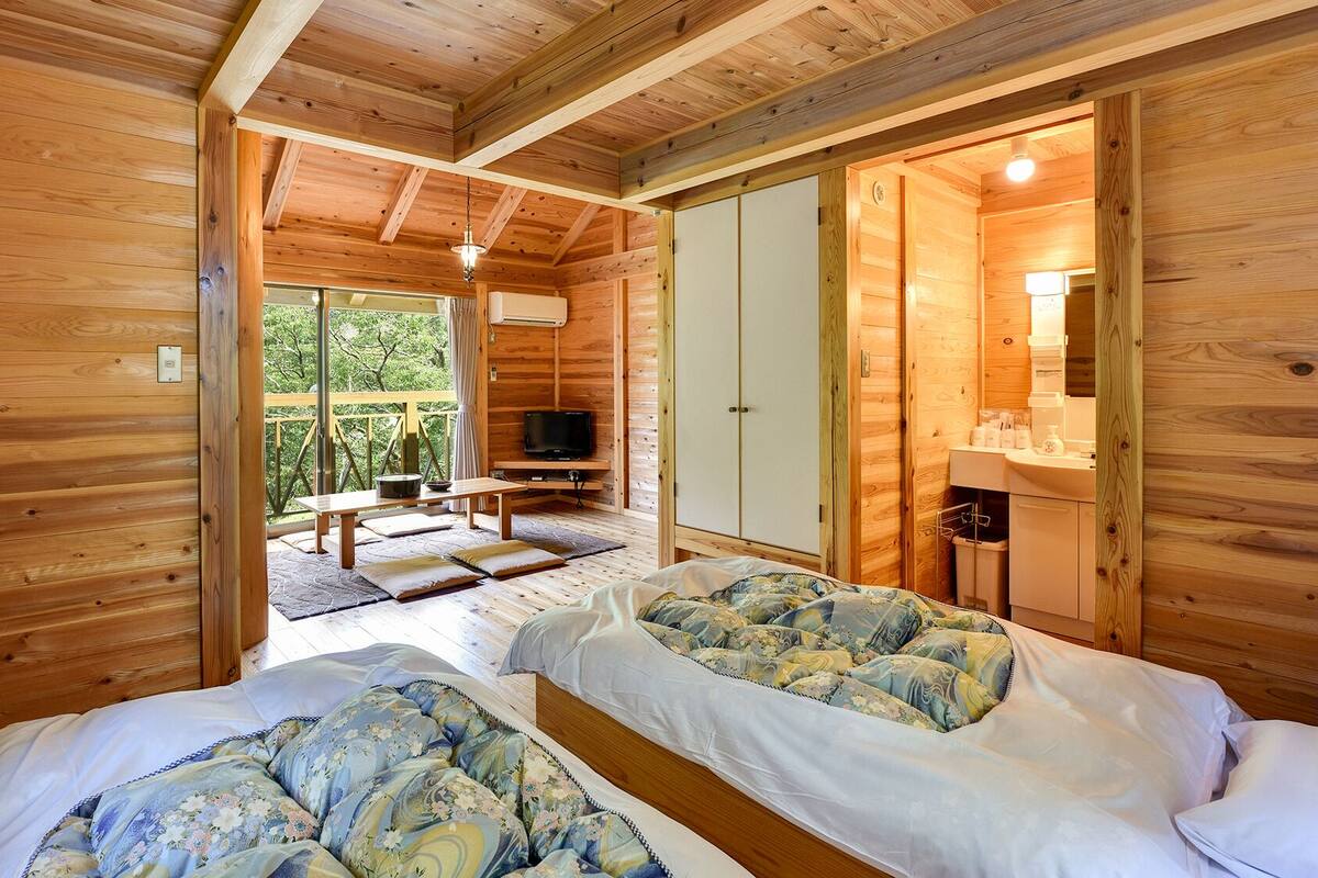 Une cabane en bois avec deux lits, une télévision et une salle de bain.