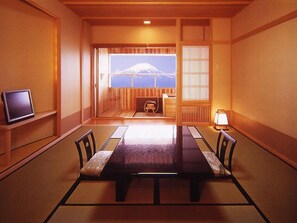 Et traditionelt japansk værelse med tatamimåtter, et lavt bord og et fjernsyn på en hylde.