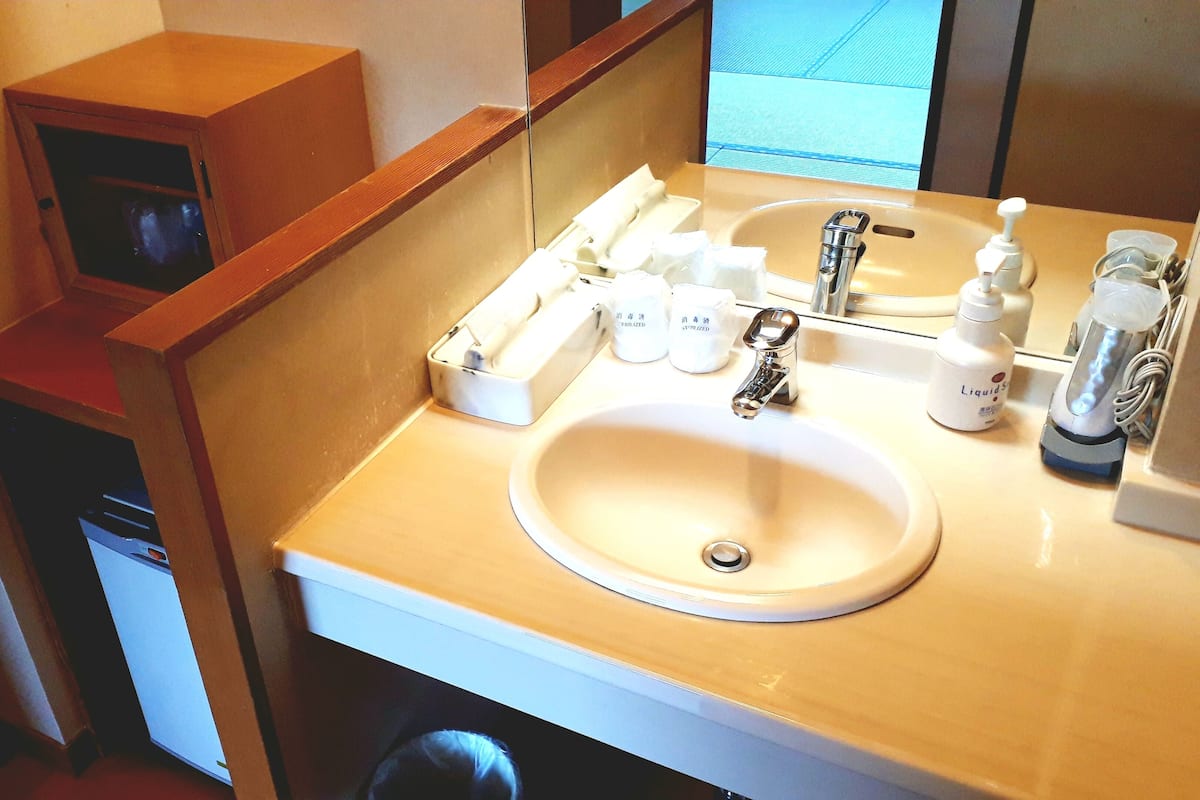 Ein Badezimmer mit Waschbecken, Spiegel und Toilettenartikeln.