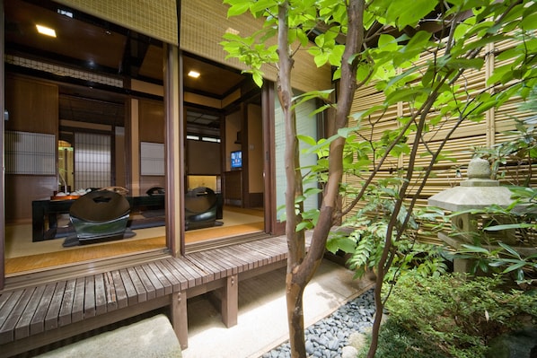 A traditional Japanese room with tatami flooring, a wooden bench, and a stone lantern.