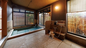 A traditional Japanese-style room with a hot spring, wooden ceiling, and large windows. - Oiwakeya Ryokan (Matsumoto)