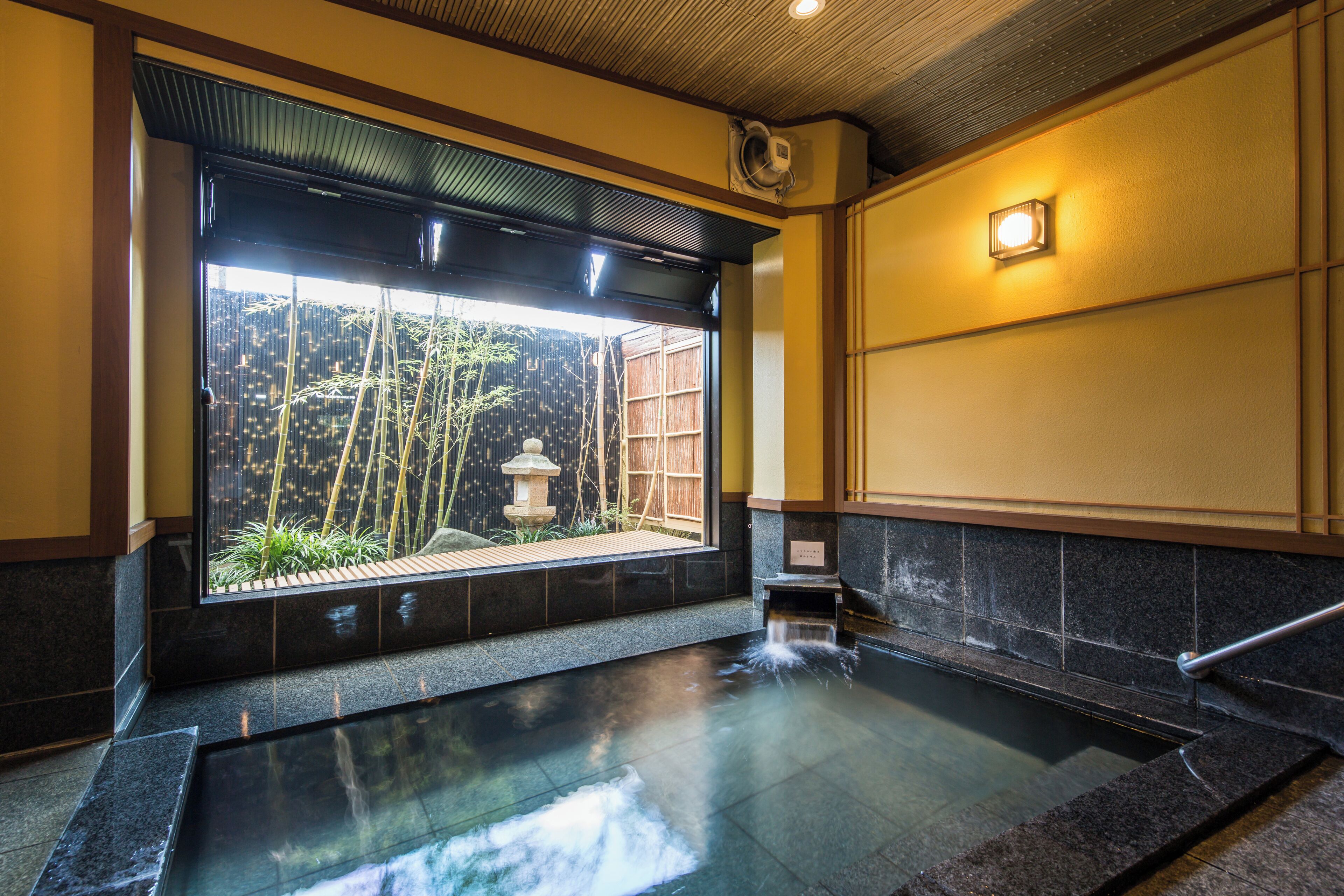 A traditional Japanese onsen with a view of bamboo outside.