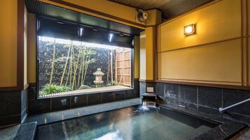 A traditional Japanese onsen with a view of bamboo outside.
