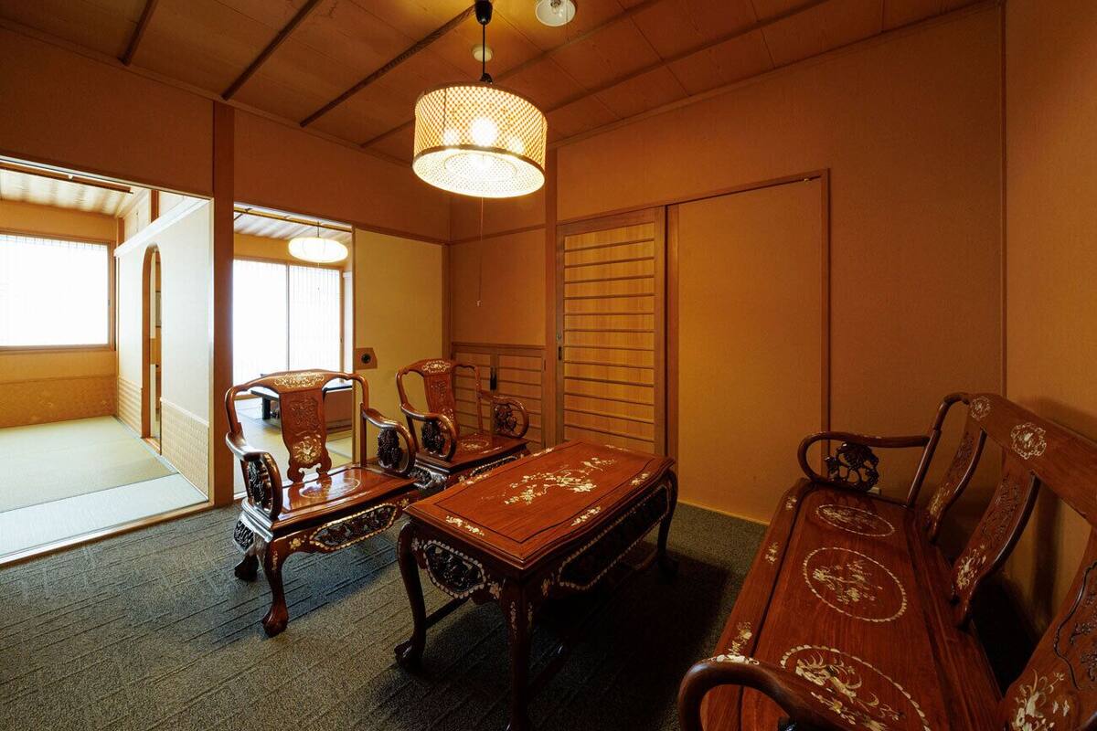 Ein traditioneller japanischer Raum mit Tatami-Böden, einem Holztisch, zwei Stühlen und einer Hängelampe.