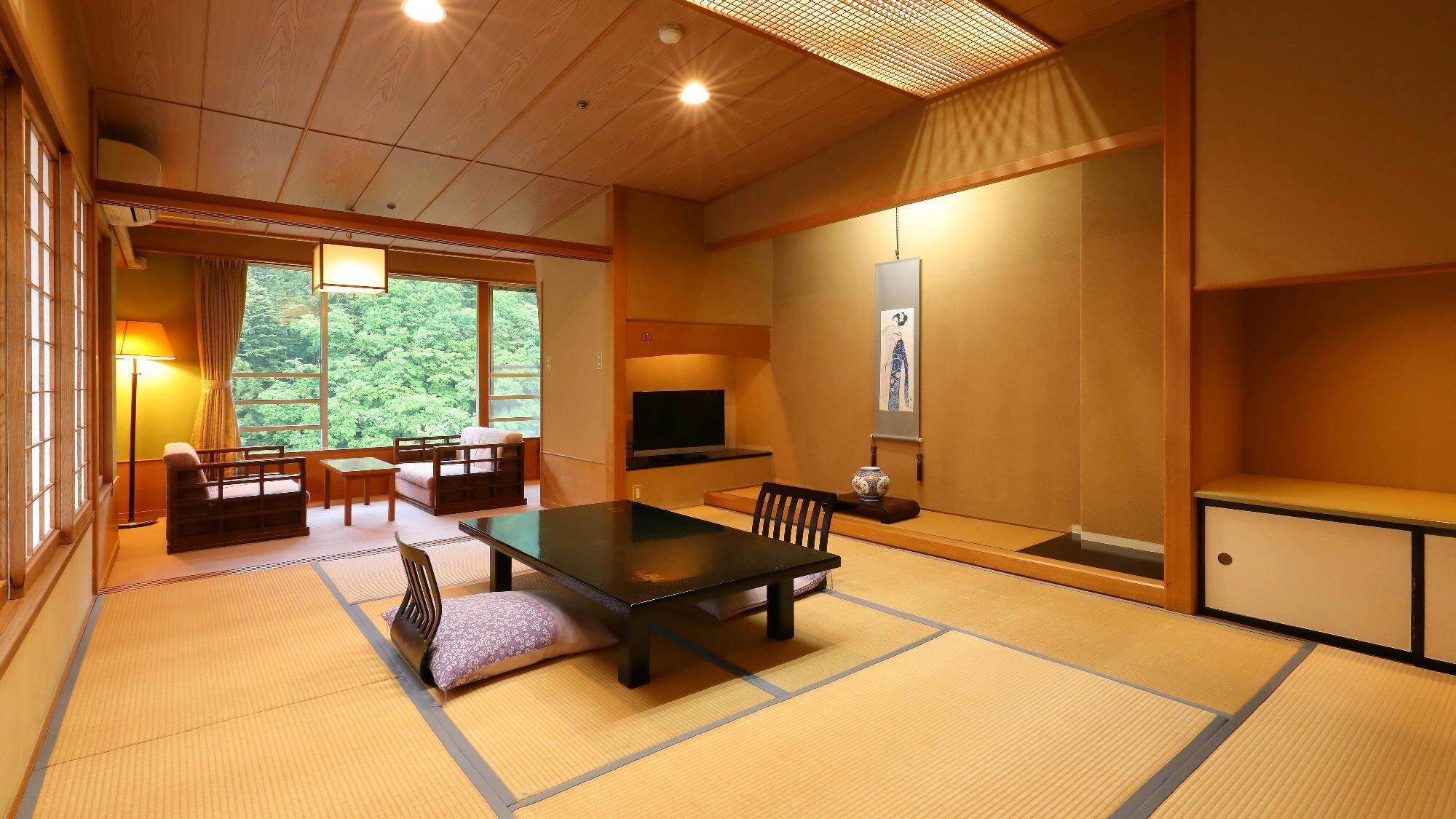 Une pièce de style japonais traditionnel, avec un sol recouvert de tatamis, une table basse, des chaises, un téléviseur et des œuvres d’art accrochées aux murs.