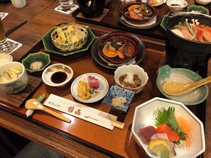Variedad de platos japoneses sobre una mesa de madera, como sushi, tempura y un tazón de sopa.