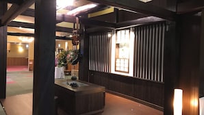 Perinteinen japanilainen huone, jossa on tatamimatto, matala puupöytä, seinälle ripustettu kukka-asetelma ja liukuva shoji-seinä.