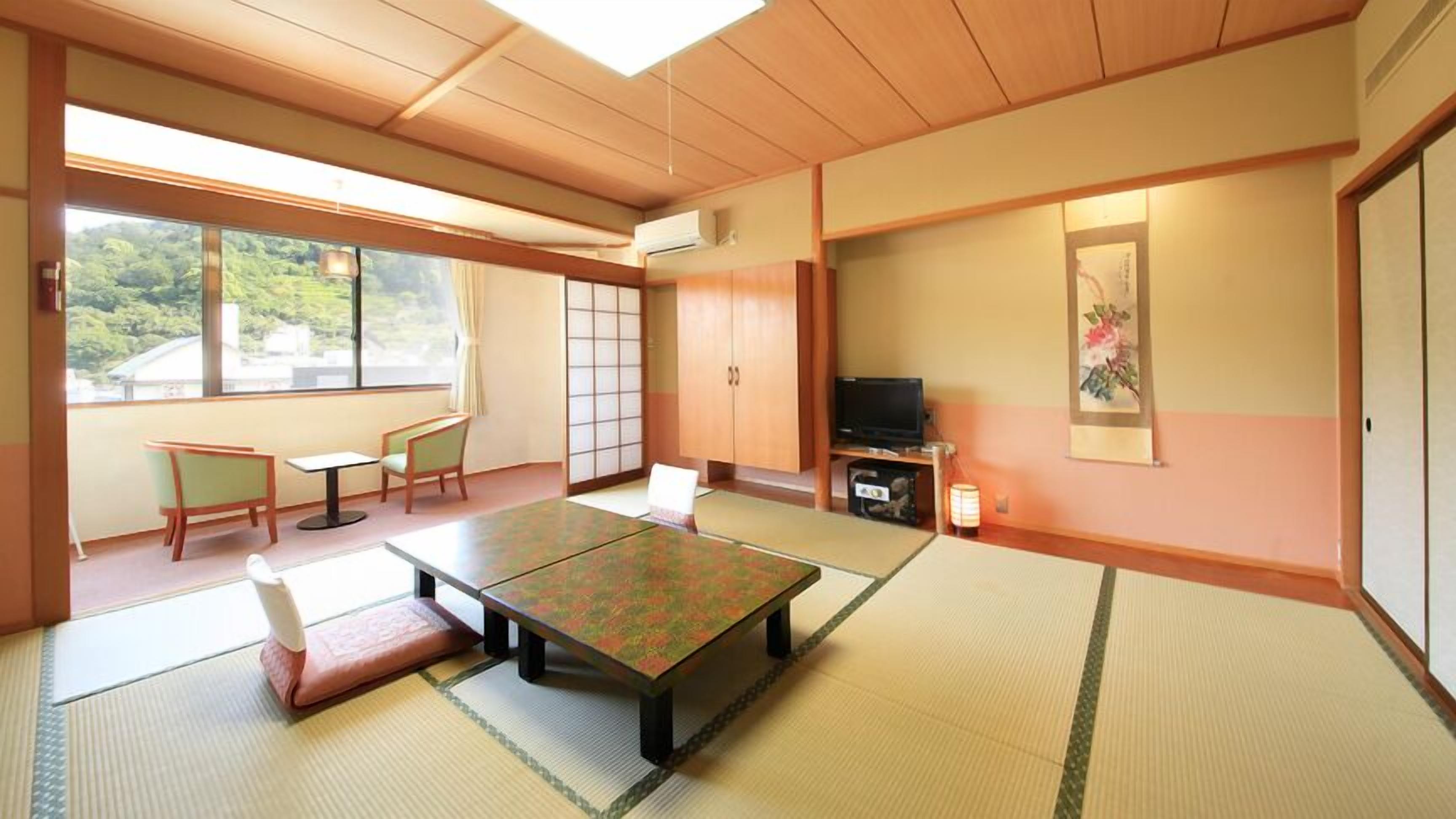 A traditional Japanese room with tatami flooring, a low table, chairs, a TV, and a sliding door.